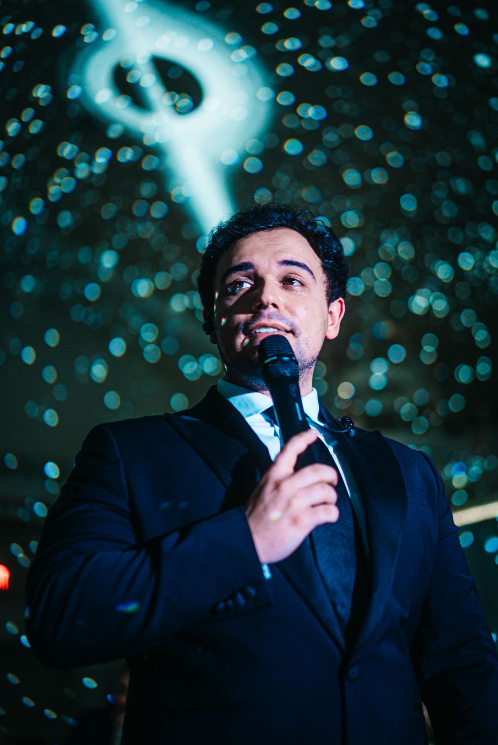A singer in a dark suit, a planet of light above him